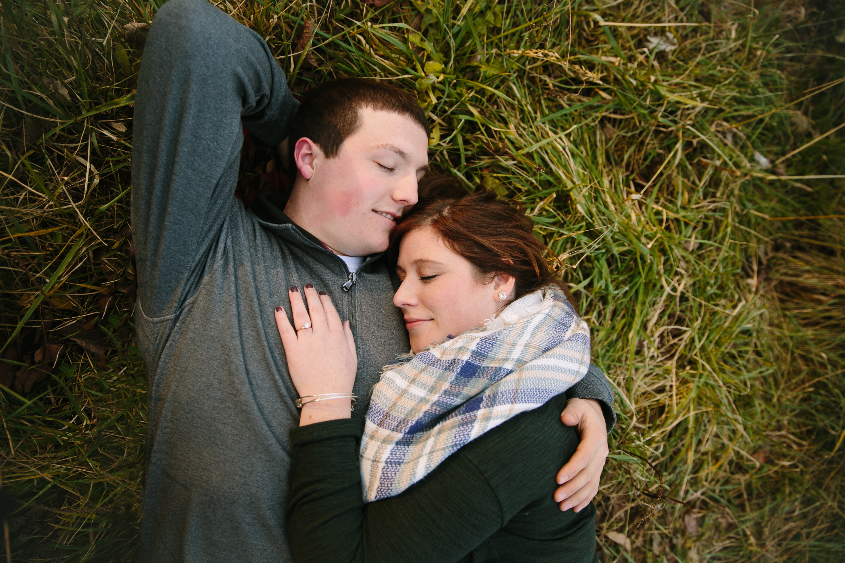 couple laying in the grass, iowa farm engagement session by catherine furlin photography