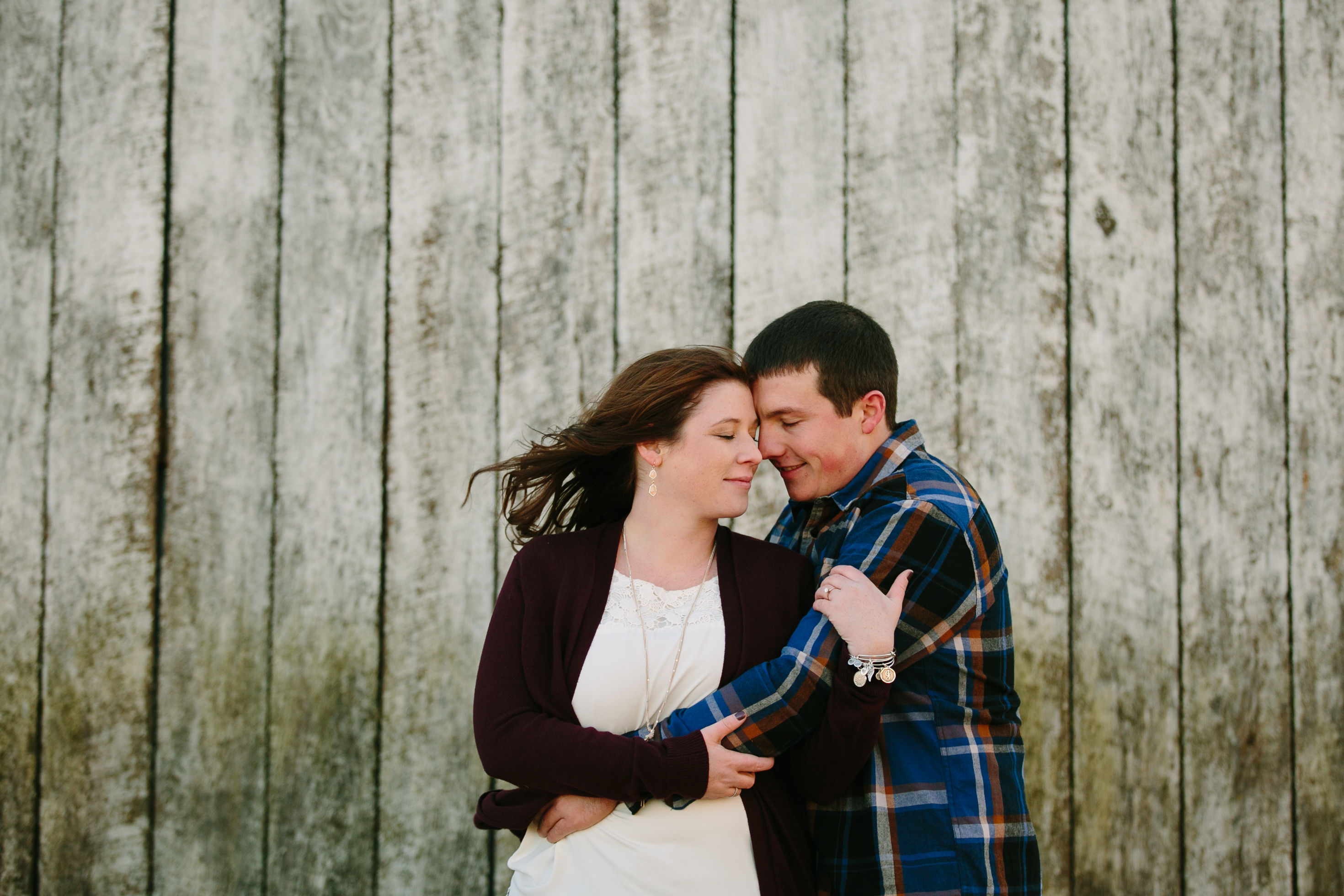 couple near a white barn, iowa farm engagement session by catherine furlin photography