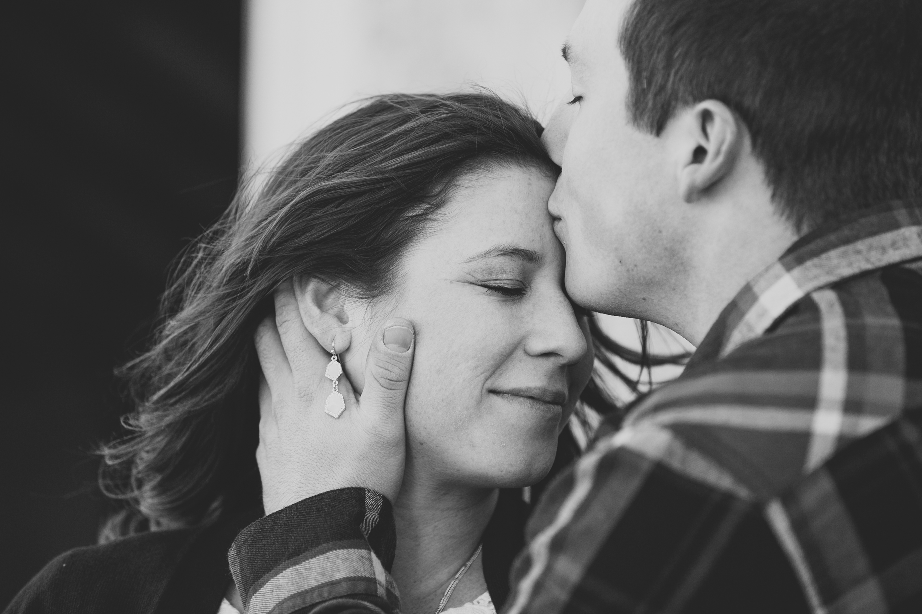 man kissing his fiance's forehead, iowa farm engagement session by catherine furlin photography