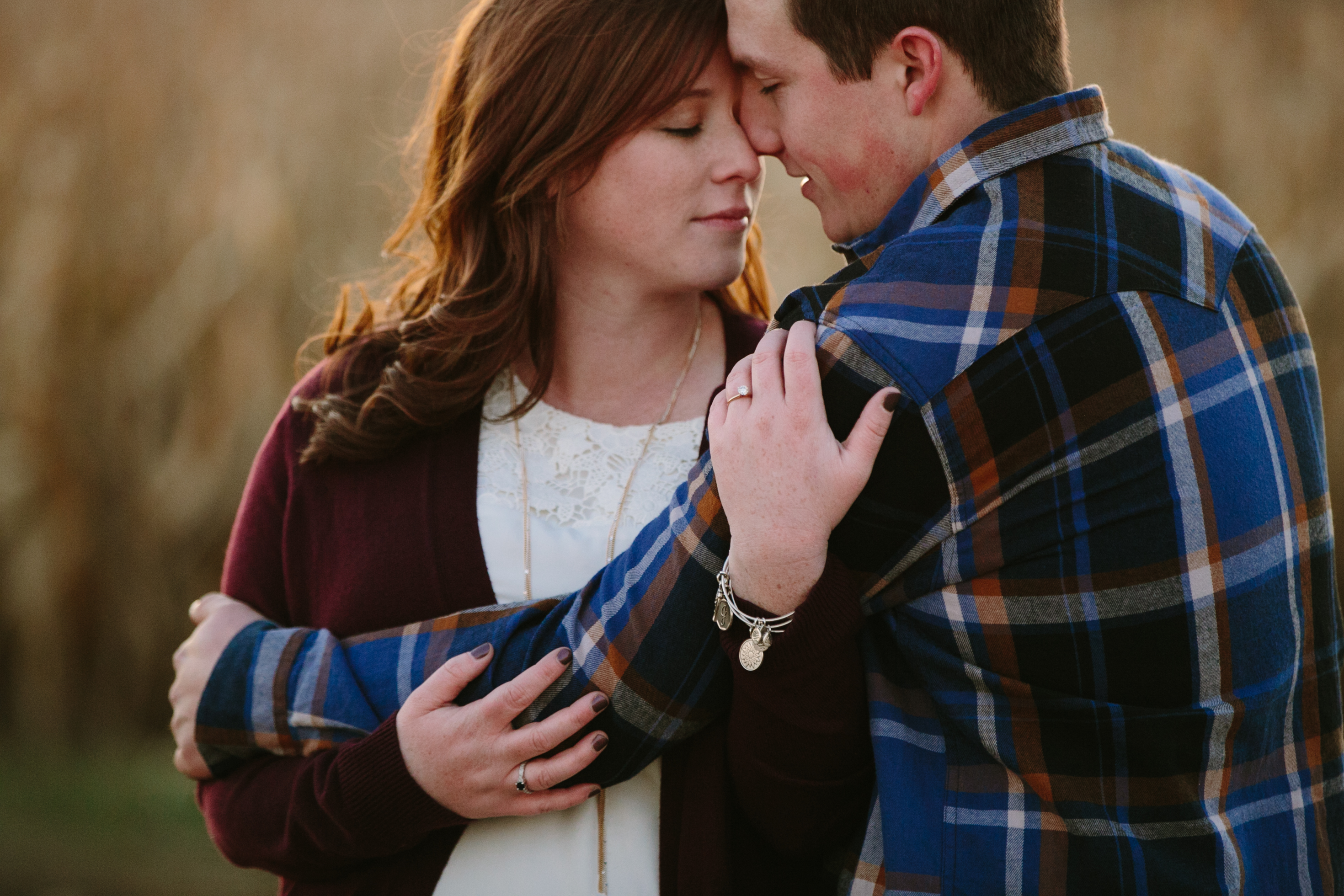 couple snuggling by corn field, iowa farm engagement session by catherine furlin photography