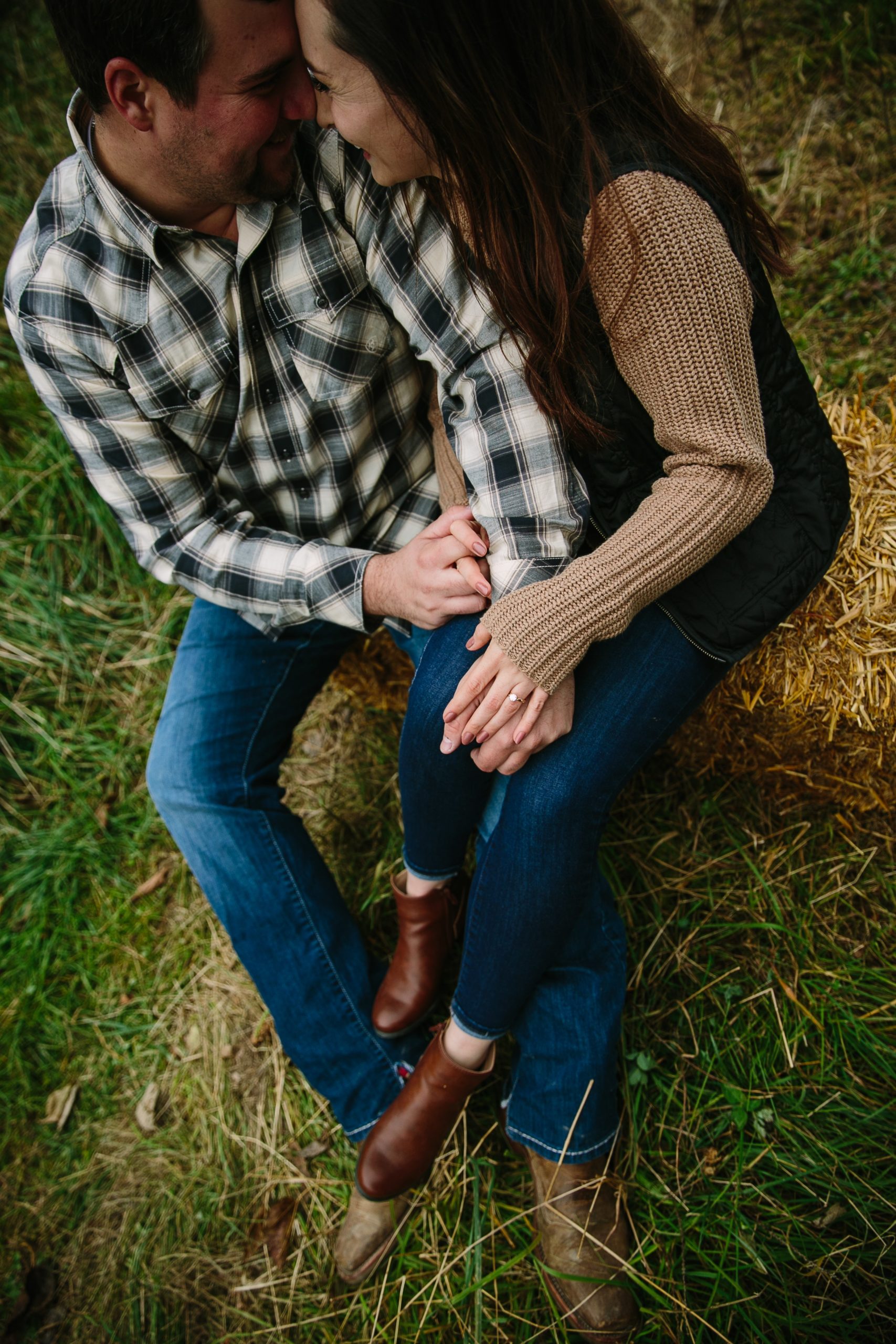 iowa couple holds hands on a bail of hay during engagement photos