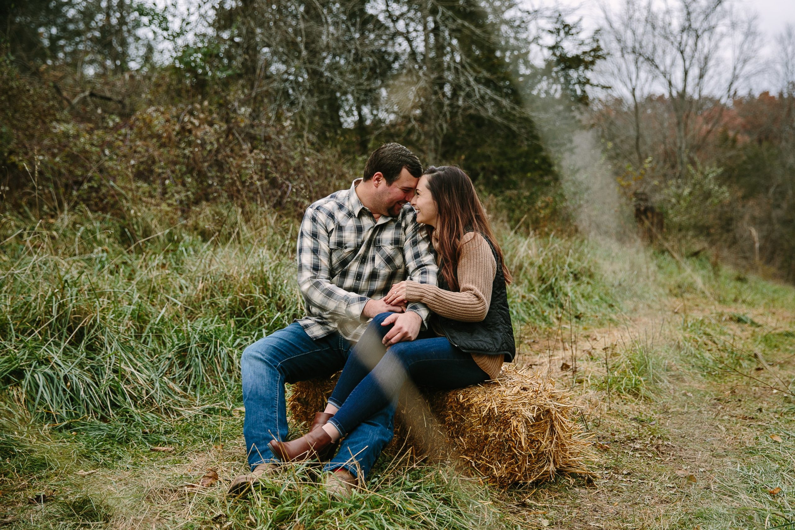 iowa couple holds hands on a bail of hay during engagement session
