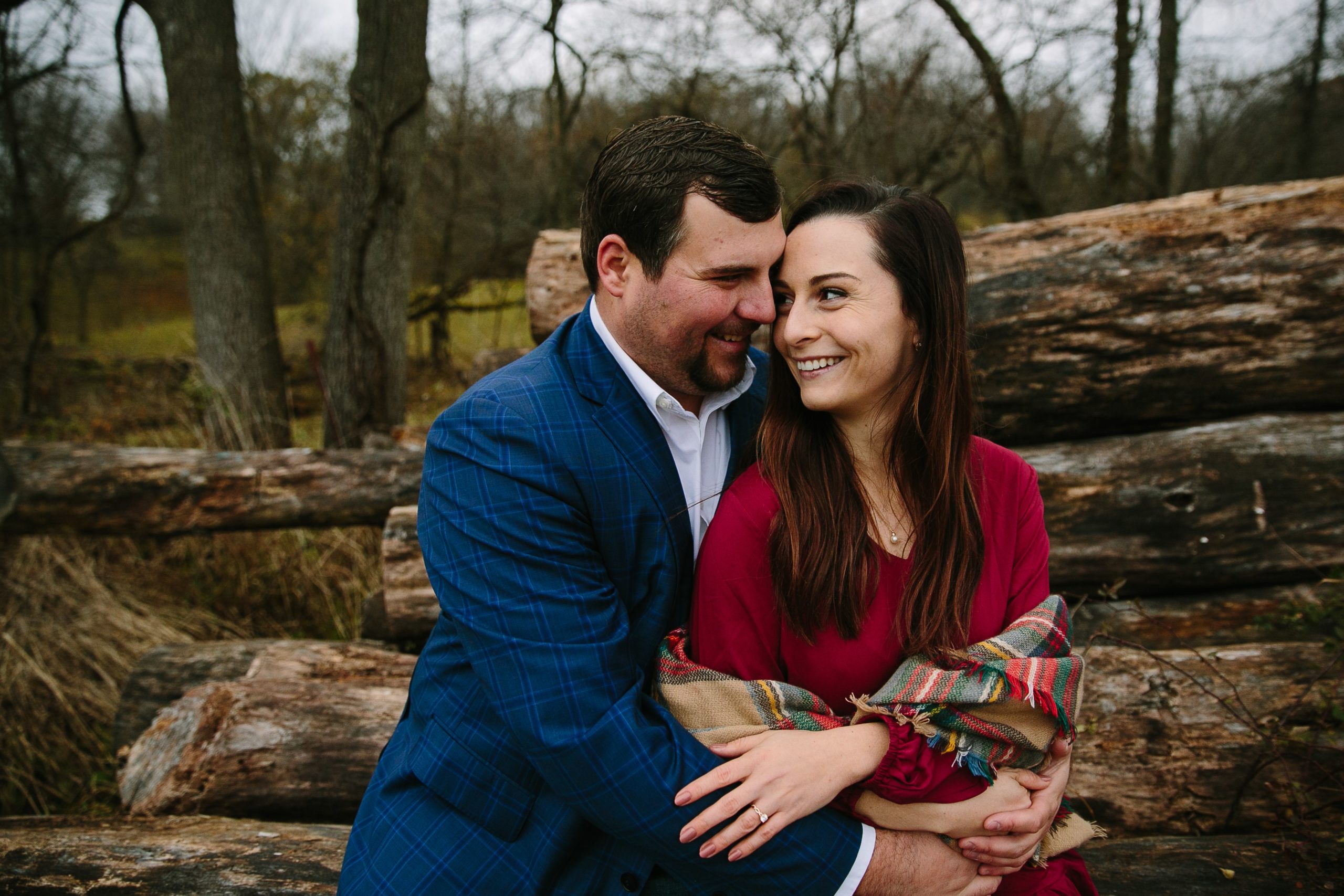 couple sitting on a pile of timber during bellevue iowa engagement photos