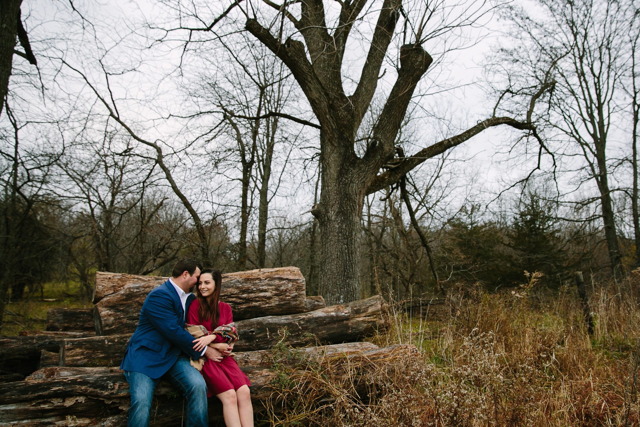 couple sitting on a pile of timber during iowa engagement session