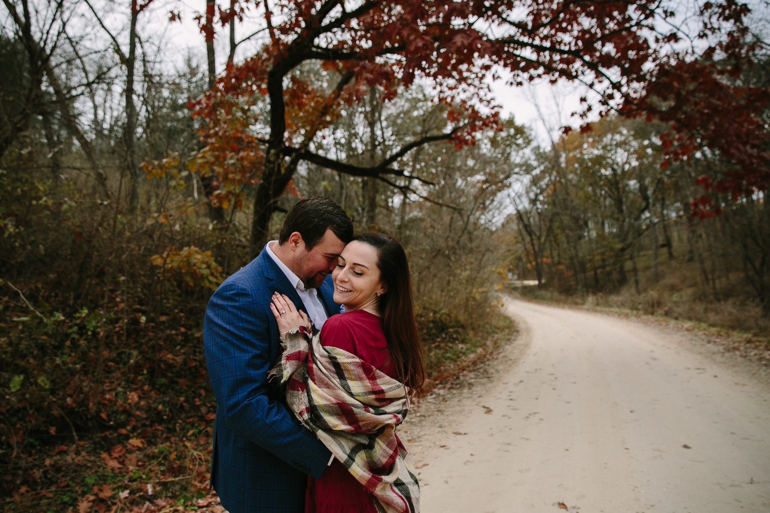 couple cuddling on a gravel road during iowa engagement session
