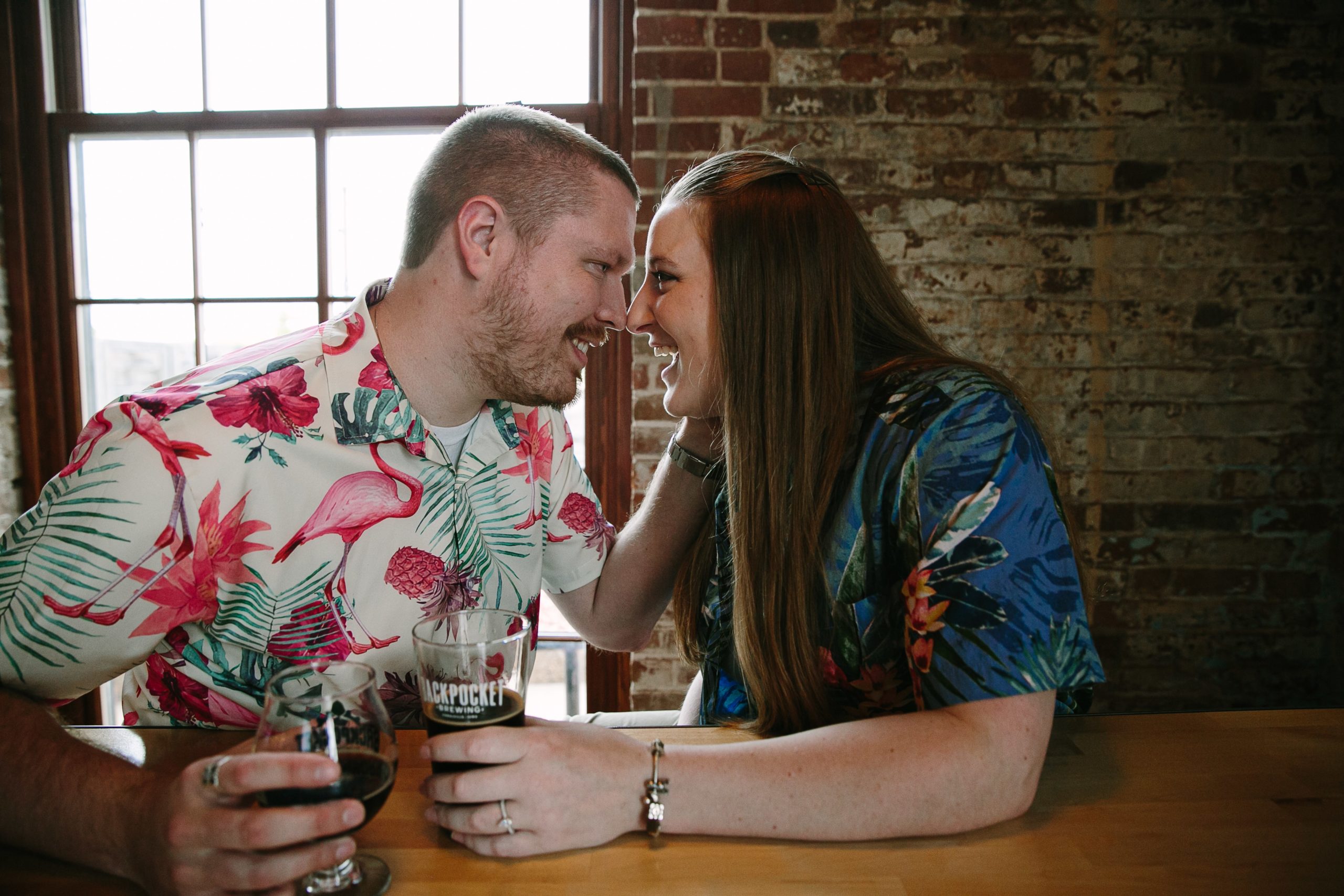 couple laughing together at backpocket brewing during dubuque engagement session