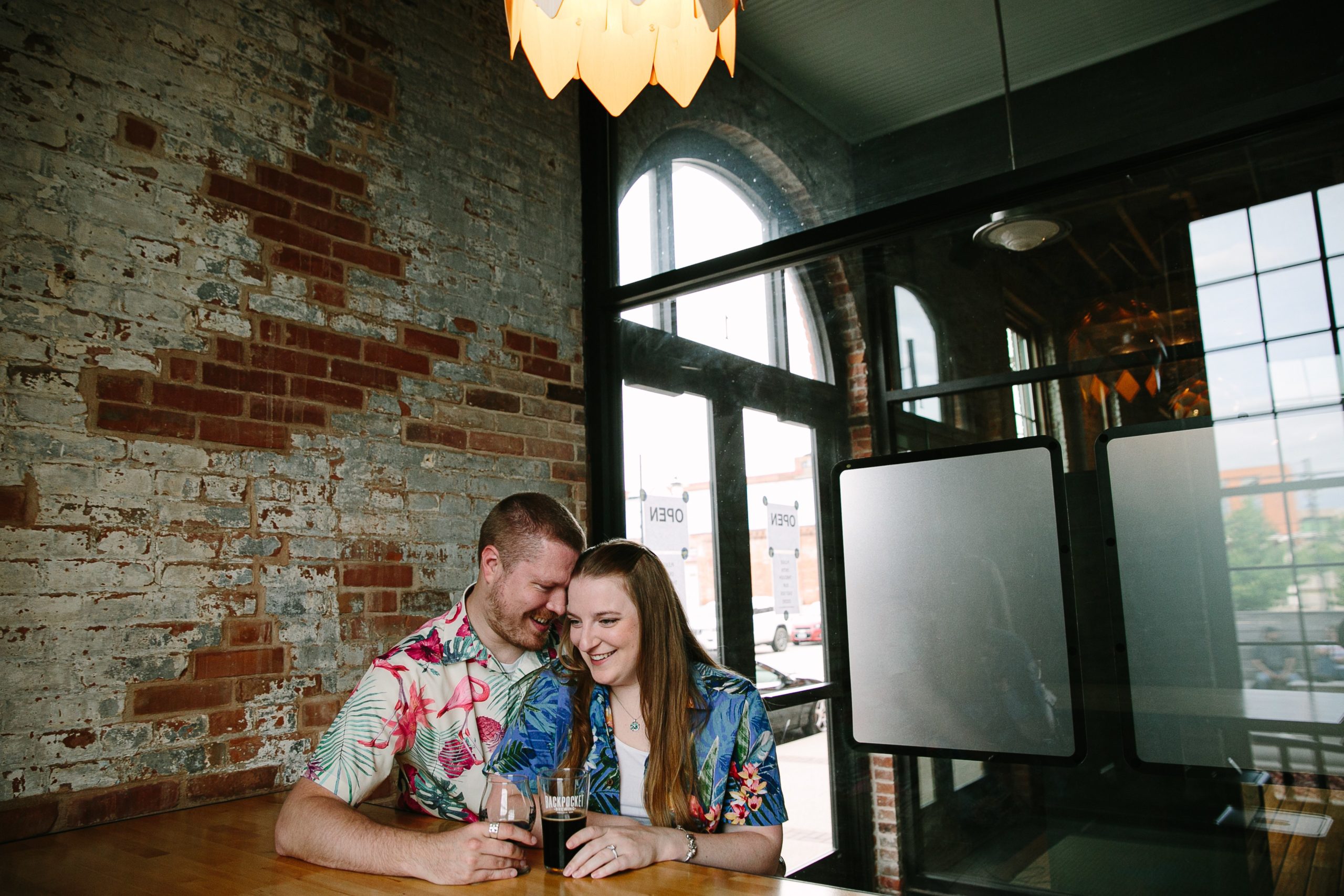 couple snuggling at table inside backpocket brewing during dubuque engagement session