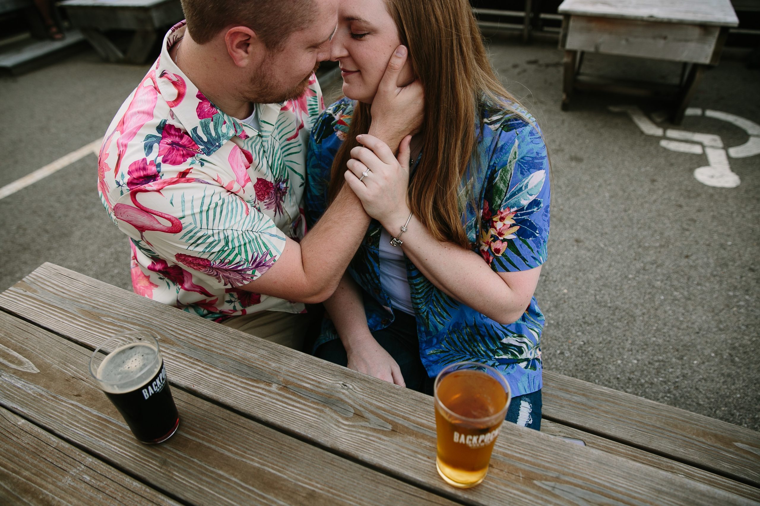 couple in hawaiian shirts sharing a draft beer togeher