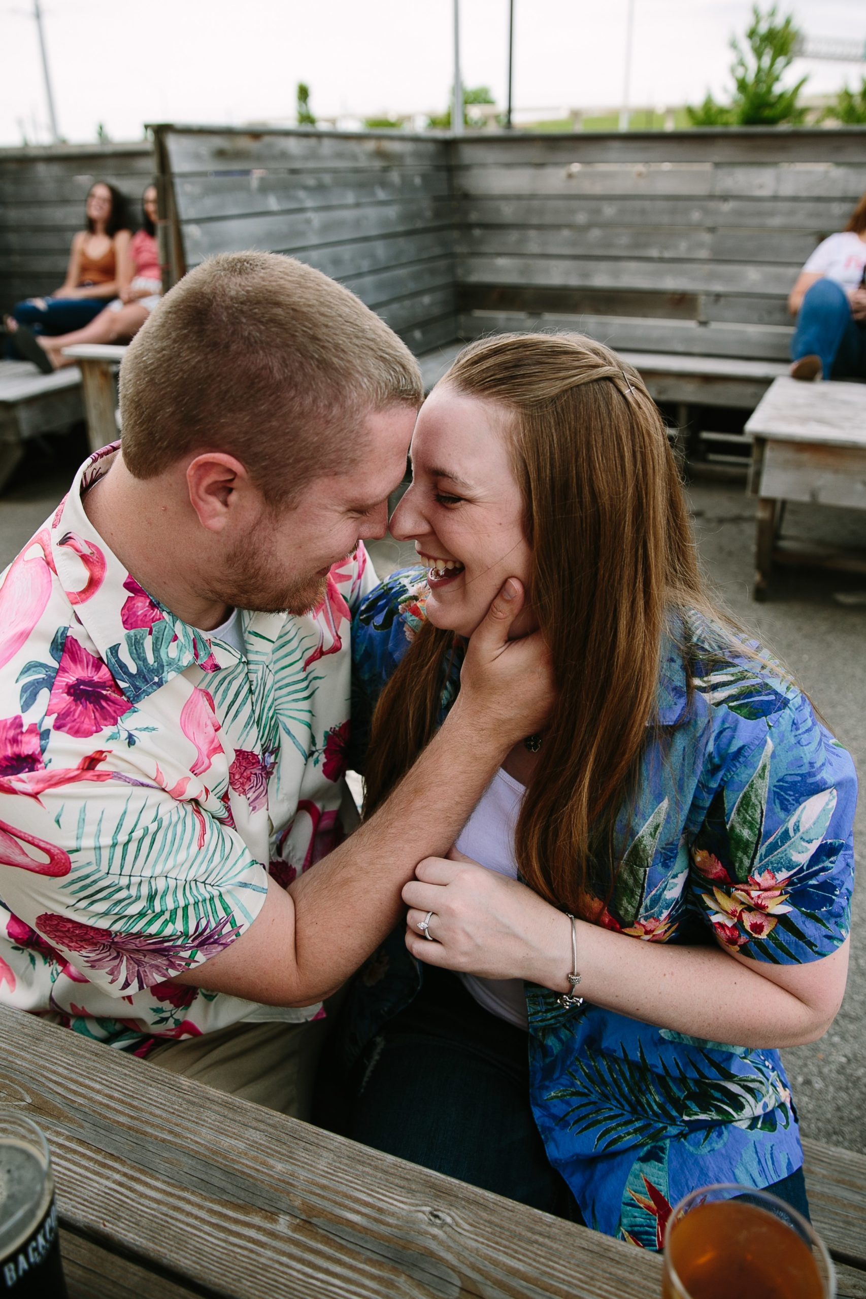 couple laughing together in outdoor patio at backpocket brewing during dubuque engagement session