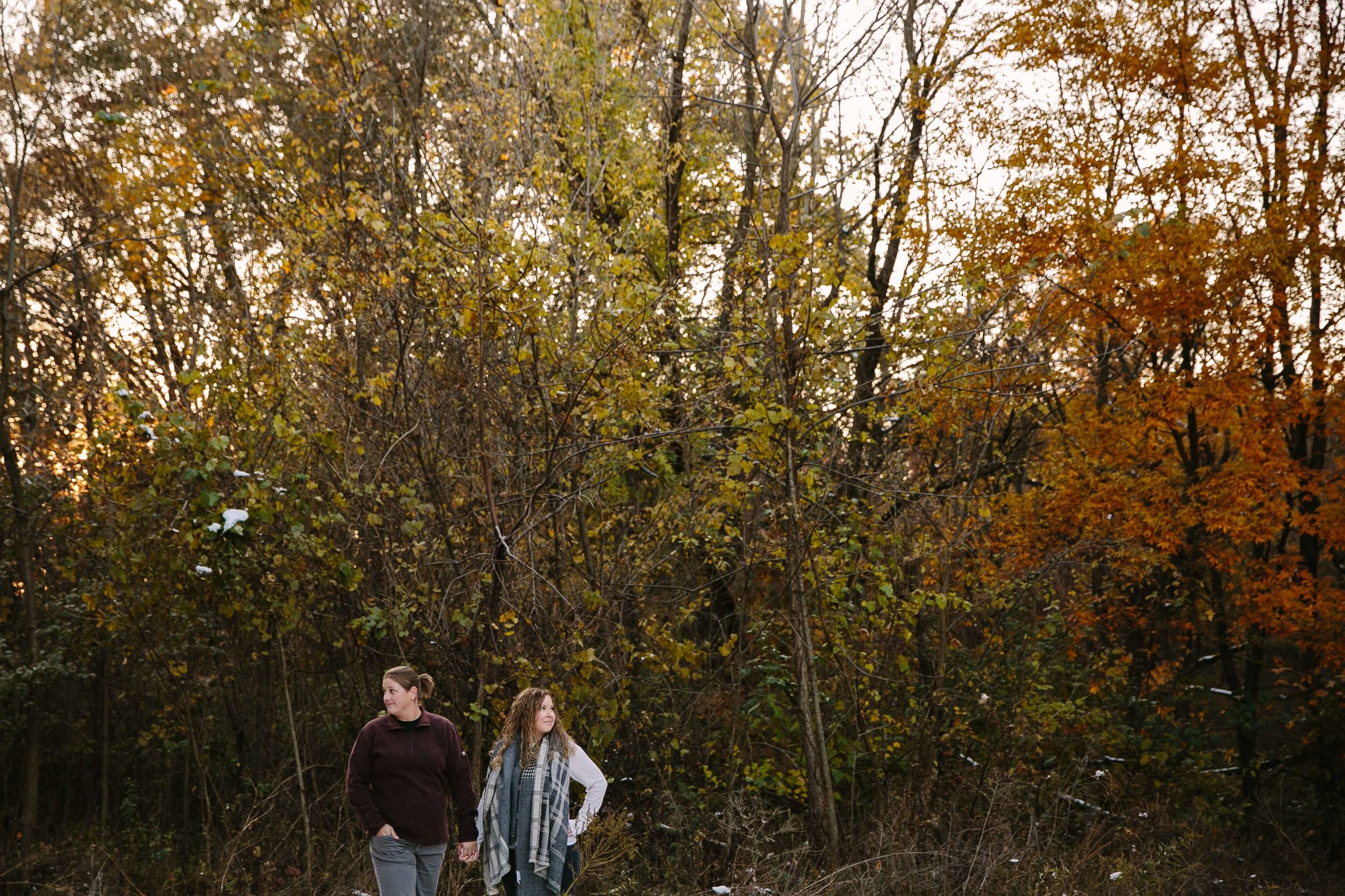 couple stands amid colorful fall leaves during their iowa engagement session