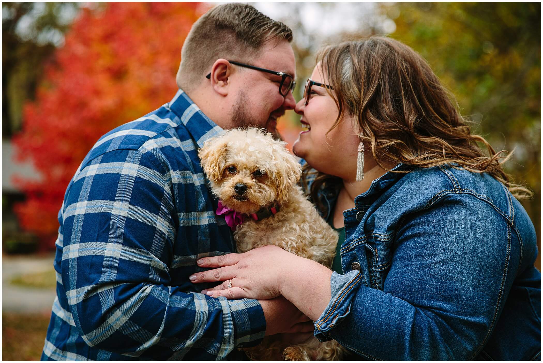 couple snuggling their dog during fall engagement session