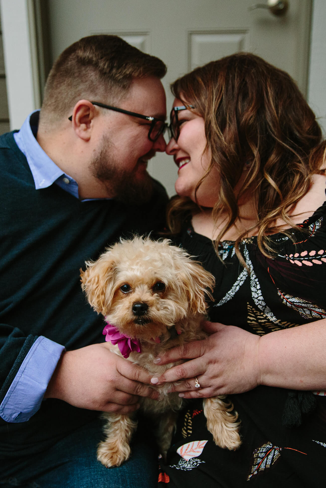 couple holding their dog on their laps during cedar falls engagement photos