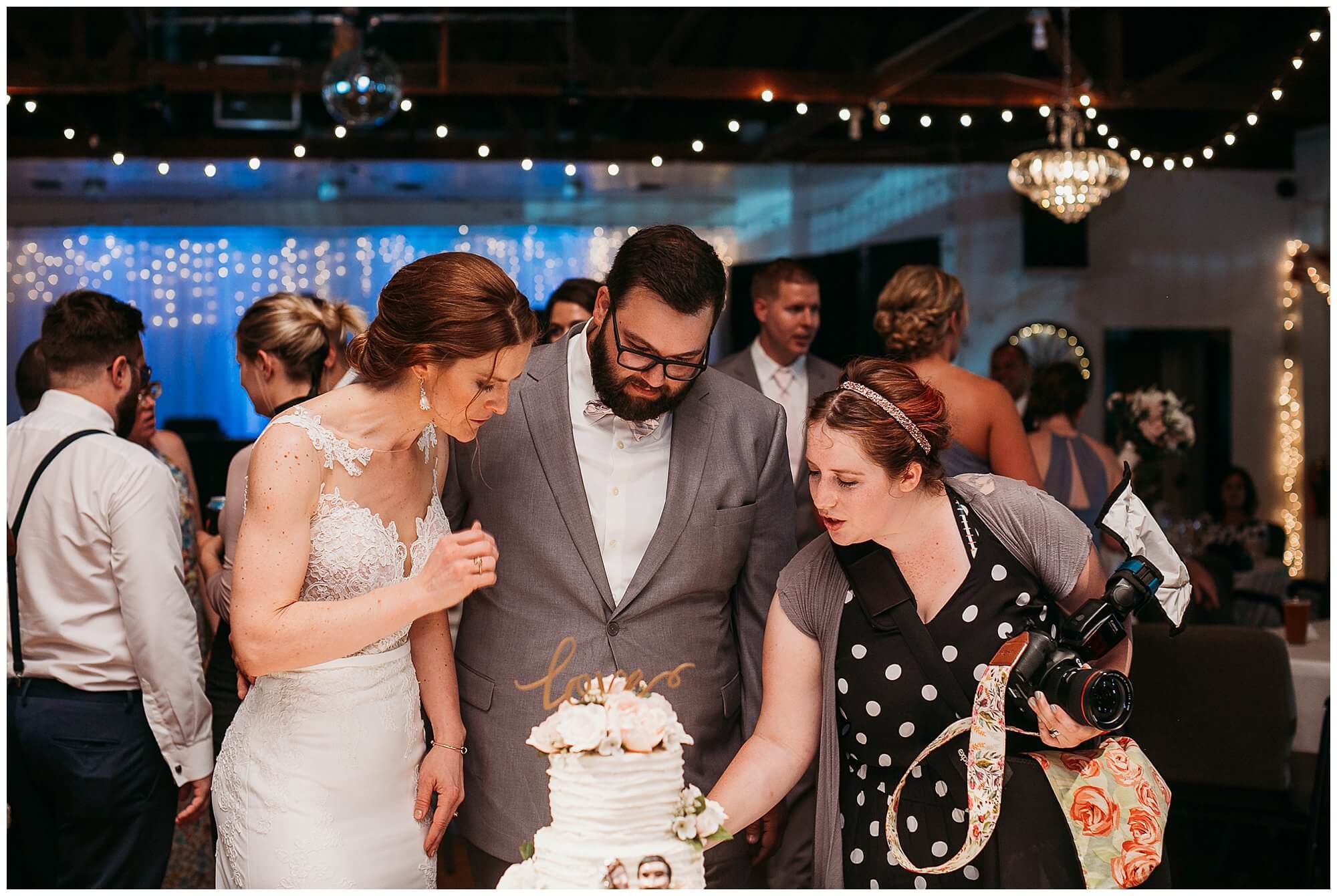 photographer helping couple during cake cutting at iowa wedding