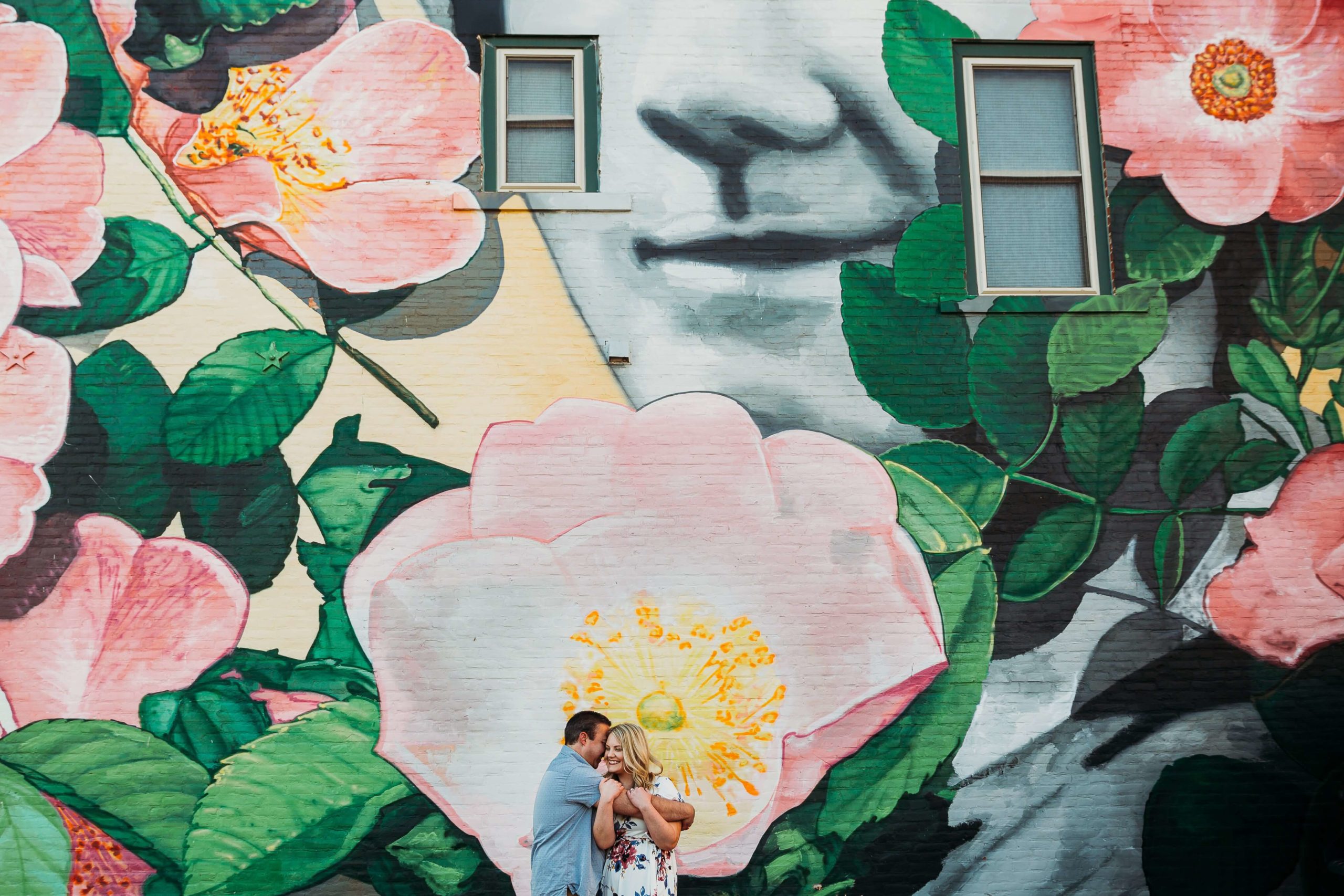 couple standing in front of a large mural during their downtown dubuque engagement photos
