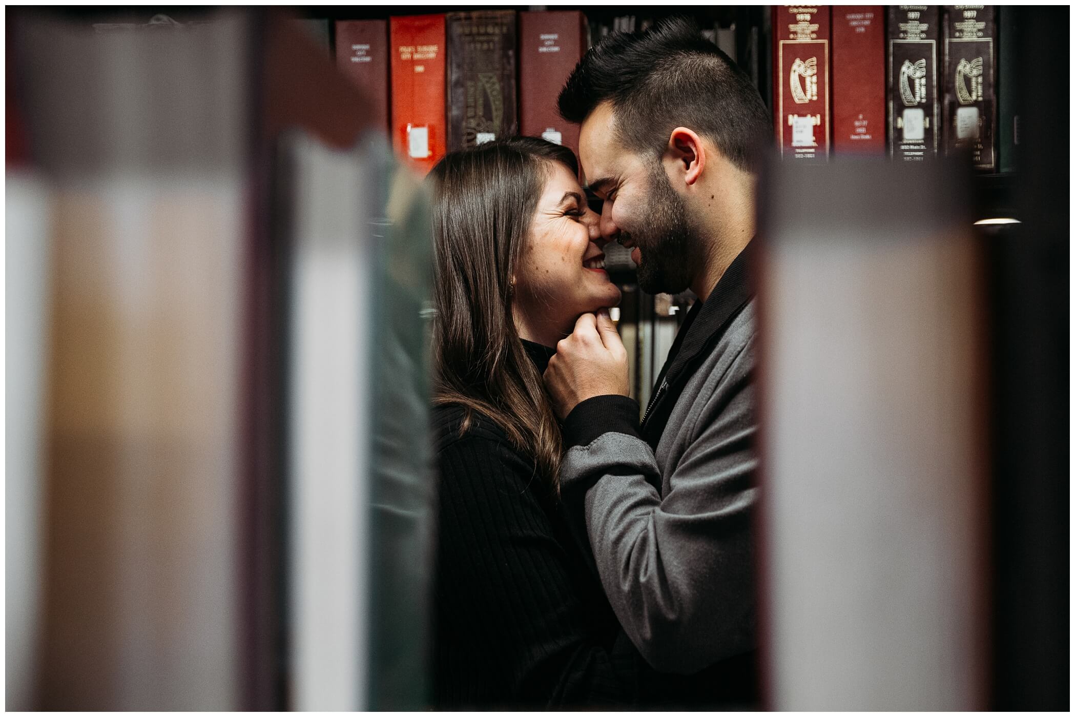 couple snuggling together in a dubuque library during their engagement photos